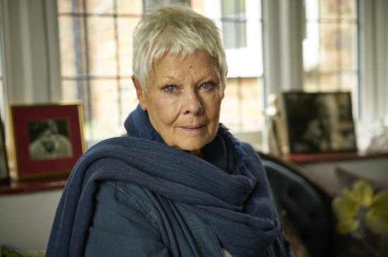 Dame Maggie Smith met een blauwe sjaal en jas, kijkend naar de camera.