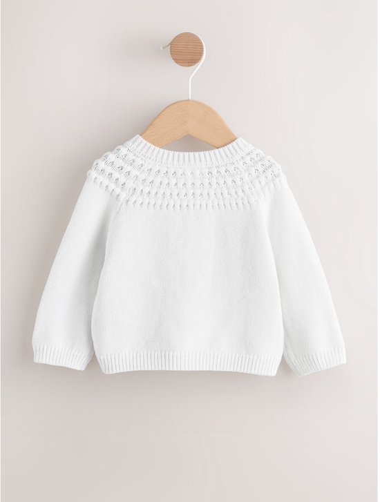 Witte babyvest met gebreide ajourdetails rond de nek.