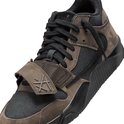 Close-up van een bruine en zwarte lage sneaker met klittenbandsluiting en veters.