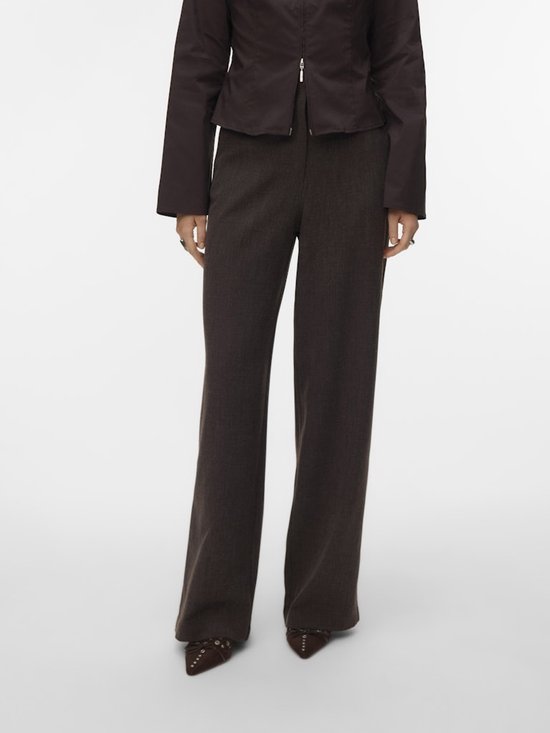Model in donkerbruine pantalon met wijde pijpen en bruine puntige schoenen.