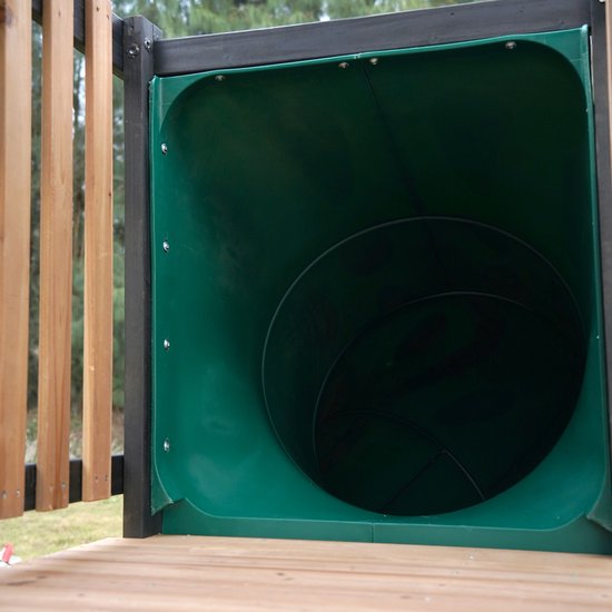 Uitzicht op de ingang van een groene buisglijbaan op een houten speeltoestel.