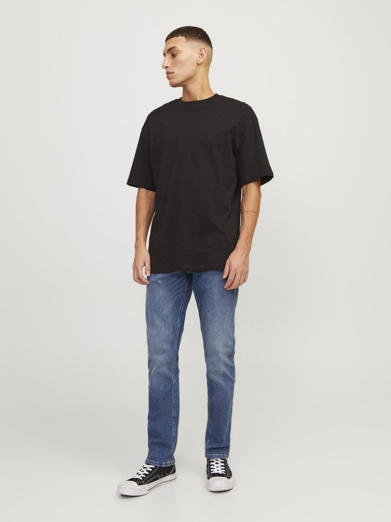 Man van de voorkant gezien, draagt een zwarte T-shirt en blauwe jeans.