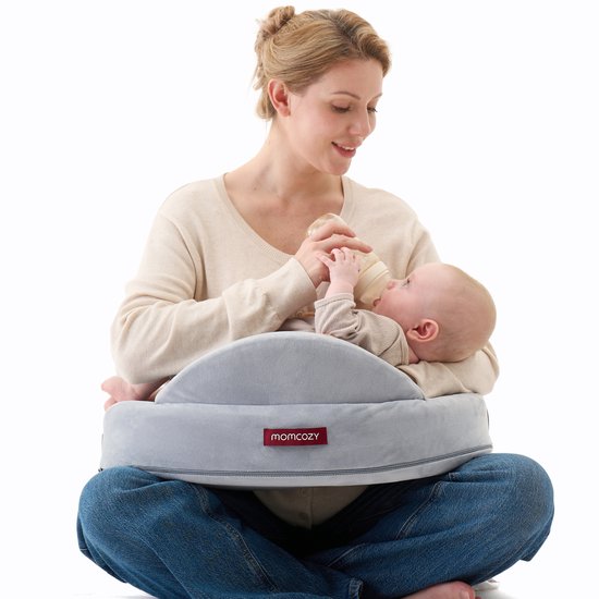 Vrouw met baby op grijze voedingskussen, voedt baby fles.
