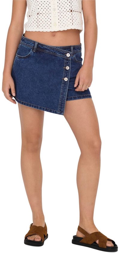 Model draagt een korte, donkerblauwe denim rok met een overslagsluiting, knopen en een asymmetrische zoom.