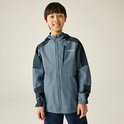 Een jongen met een grijze en donkerblauwe jas met capuchon en een teddybeer op zijn rug.