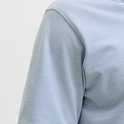 Close-up van de schouder en mouw van een lichtblauw poloshirt.