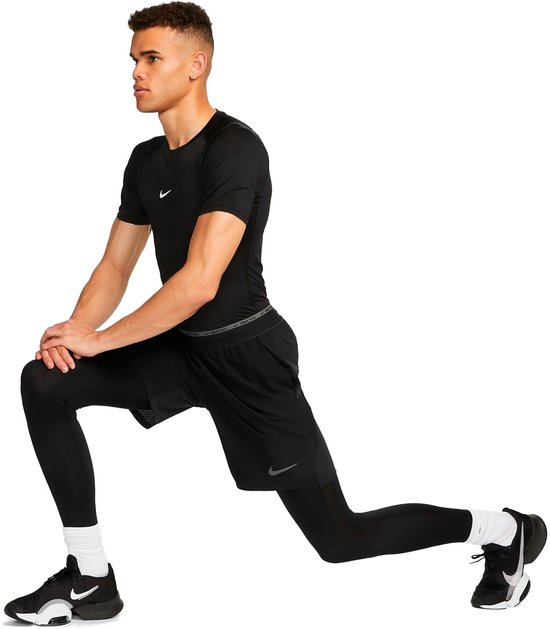 Man in een zwarte Nike Pro Dri-FIT shirt, zwarte shorts en zwarte compressiebroek, in een longeerhouding.
