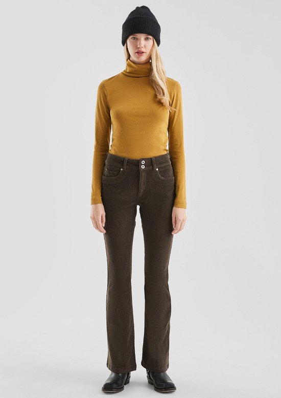Model in okergele coltrui, bruine corduroy bootcut broek met hoge taille en zwarte muts.