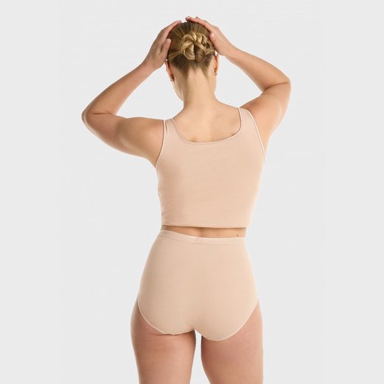 Model van achteren, met de handen in het blonde opgestoken haar. Beige top en hoge slip.