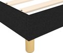 Detail van de hoek van een zwart boxspring bedframe met ronde houten poot.
