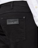 Zwarte jeans met Wrangler logo patch op de achterzak.