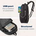 Donkergrijze rugzak met een USB-poort aan de zijkant, waar een telefoon aan is opgeladen. De rugzak is open, met inhoud.