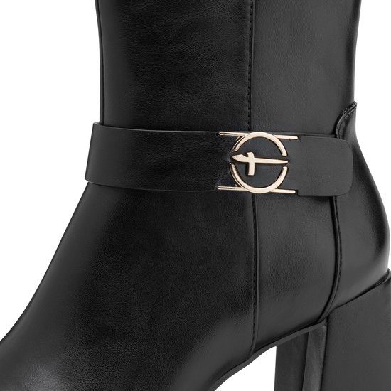 Detail van zwarte enkellaars met gesp en goudkleurig logo op de band.