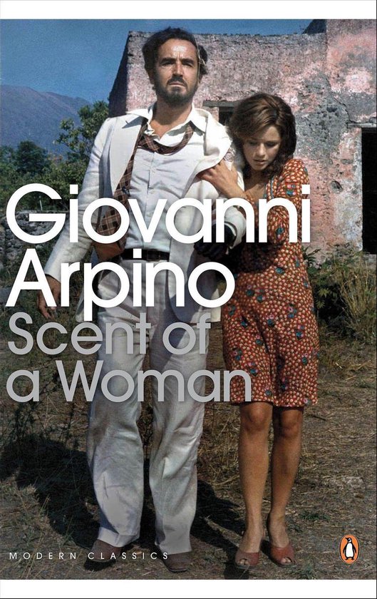Un homme en costume blanc avec une chemise à rayures et une femme en robe à fleurs orange se tiennent ensemble devant un bâtiment délabré.