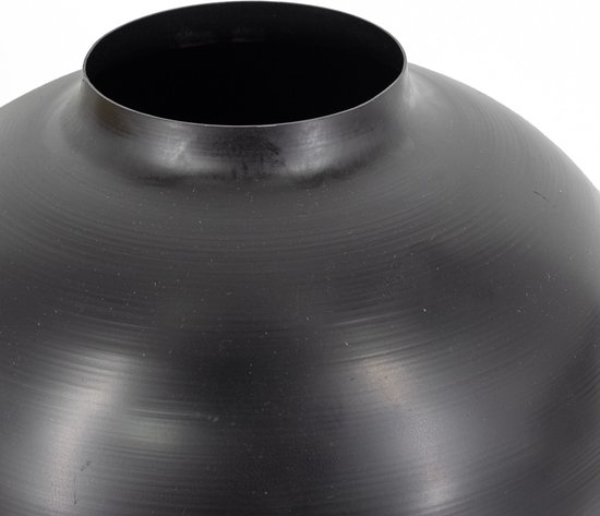 Close-up van de ronde, zwarte metalen vaas. De vaas heeft een smalle opening en een gebogen, geborsteld oppervlak.