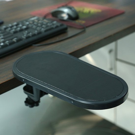 Zwarte, ovale bureau-armsteun met klem bevestigd aan een houten bureau, naast een toetsenbord en muis.