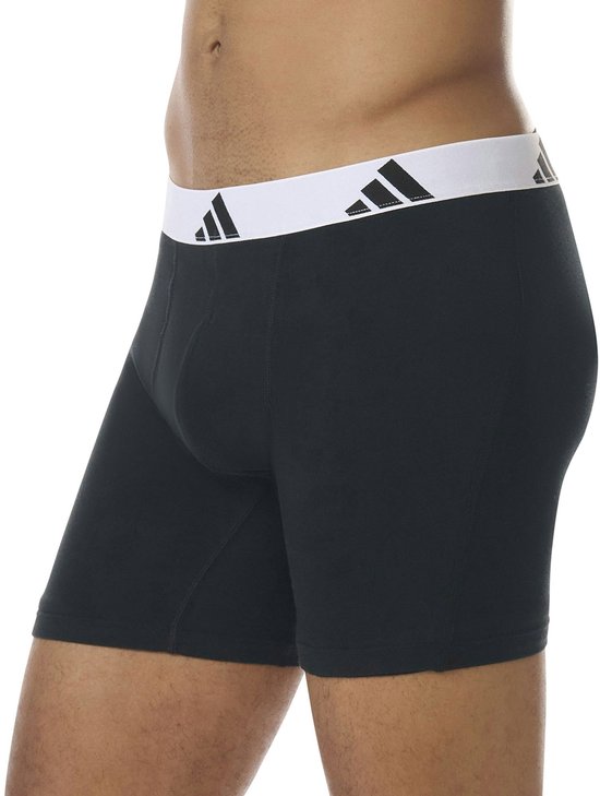 Zijkant van zwarte boxershorts met brede, witte Adidas-band met logo's.