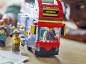 LEGO dubbeldekker bus met bestuurder en passagier, met 'Museum' en 'Downtown' bordjes.