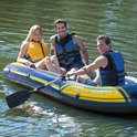Drie mensen in een blauwe Intex Challenger 3 boot met gele accenten, op het water.