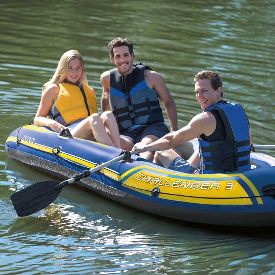 Drie mensen in een blauwe Intex Challenger 3 boot met gele accenten, op het water.