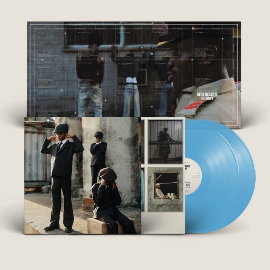 Disque vinyle bleu avec une couverture montrant un groupe d'hommes en costume et une partie de la liste des pistes. La couverture est partiellement ouverte, avec l'image d'un homme dans une fenêtre.