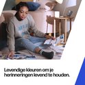 Een jonge vrouw zit op de grond en bekijkt foto's.
