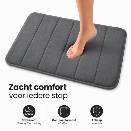 Tapis de bain gris côtelé, avec un pied qui monte dessus. Le tapis a un rembourrage en mousse à mémoire de forme.