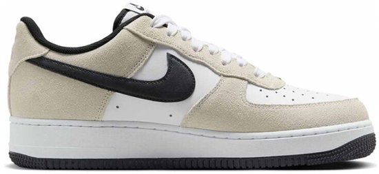 Witte sneaker met beige suède overlays, zwart Swoosh-logo en "AIR" op de zool.