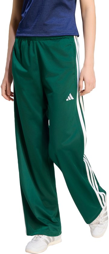Donkergroene trainingsbroek voor dames met witte Adidas strepen op de zijkant en een Adidas logo.