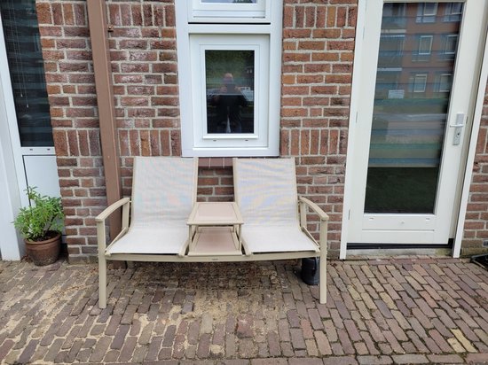 Beige aluminium tuinbank met stoffen zitting en middenplateau, staand op een terras.