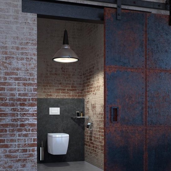 Een toiletrolhouder van chroom hangt naast een modern vierkant toilet in een industriële badkamer.