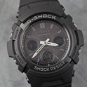 Gedetailleerde weergave van een zwart G-Shock horloge met donkergrijs display, analoge wijzers en digitale sub-dials. 'SHOCK RESIST' is zichtbaar.
