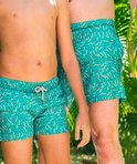 Jongens in turquoise zwembroeken met wit patroon, staand bij een zwembad.