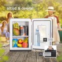 Compacte zwarte minikoelkast met fruit en blikjes, buiten bij zonnig weer met mensen op de achtergrond.