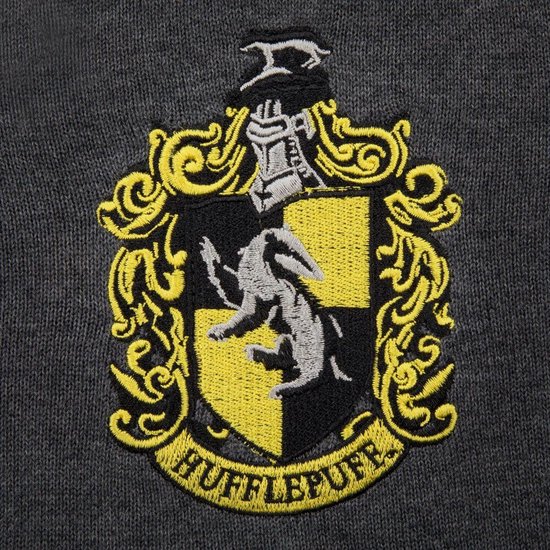 Detailopname van het geborduurde Hufflepuff wapenschild met leeuw en de tekst 'HUFFLEPUFF'.