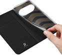 Une main détache la coque transparente à motif ondulé doré de l'étui portefeuille noir ouvert.