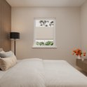 Une chambre avec un store plissé couleur sable, un lit et une lampe sur pied.