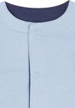 Detail van de sluiting van een lichtblauw vestje met donkerblauwe boord en knopen.