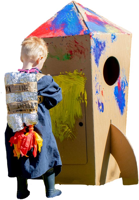 Jongetje met zelfgemaakte rugzak schildert op een kartonnen raket. De raket is versierd met primaire kleuren.