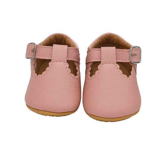 Vooraanzicht van roze babyschoentjes met gesp en geschulpte randen.