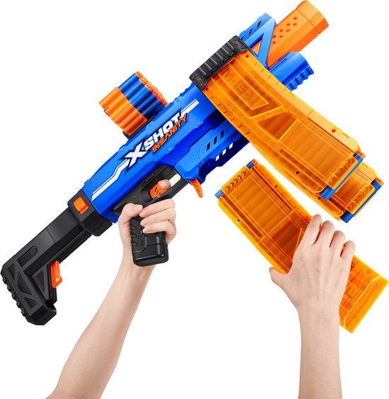 Handen die een blauwe X-Shot Insanity blaster vasthouden. De blaster heeft twee doorzichtige oranje magazijnen en een extra magazijn erbovenop.