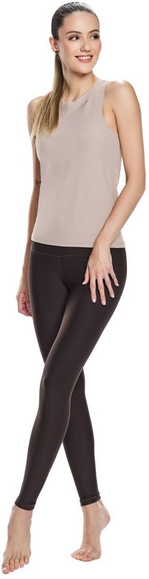 Model in een lichtbruin sporttanktop en donkerbruine legging.