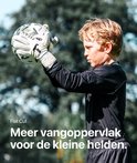 Jongen met zwart keepersshirt en witte Titan handschoenen vangt een bal.