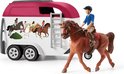 Speelfiguur van een ruiter op een bruin paard, naast een witte paardentrailer met paardenafbeeldingen.