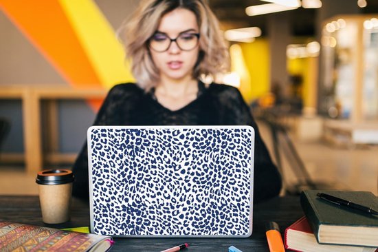 Femme avec des lunettes travaille sur un ordinateur portable avec un imprimé léopard bleu.