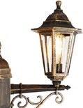 Een detail van een antieke lantaarn met glazen panelen en een gloeilamp, goud/messing kleurig.