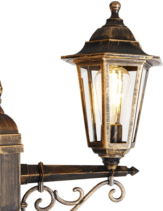 Een detail van een antieke lantaarn met glazen panelen en een gloeilamp, goud/messing kleurig.