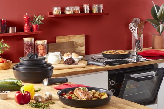 Keuken interieur met stapelbare zwarte pannen, geroosterd vlees, ovenschotel en bakbenodigdheden.