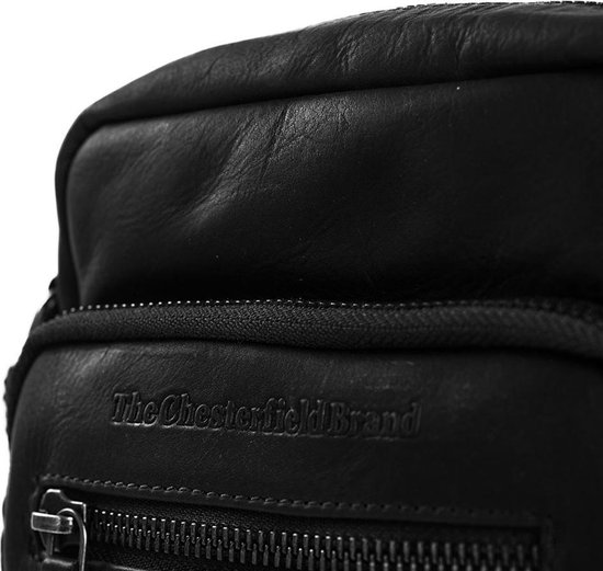 Close-up van het logo 'The Chesterfield Brand' op een zwarte leren schoudertas.