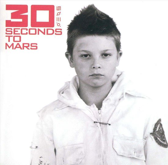 Jongen met kuif, witte jas met rits, kijkt ernstig naar de camera. Logo '30 Seconds To Mars' in rode letters.